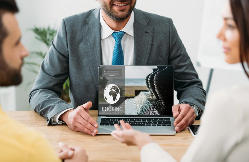 a travel advisor holding a laptop in front of a couple