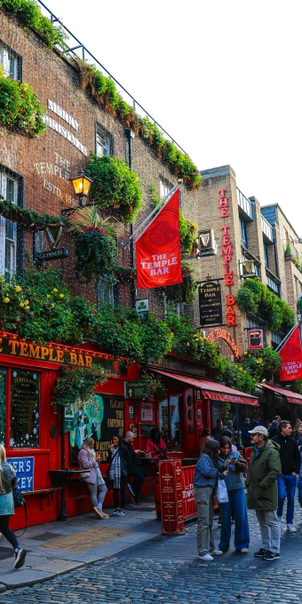 Traditional red Dublin pub facade on a lively city street in Ireland.
